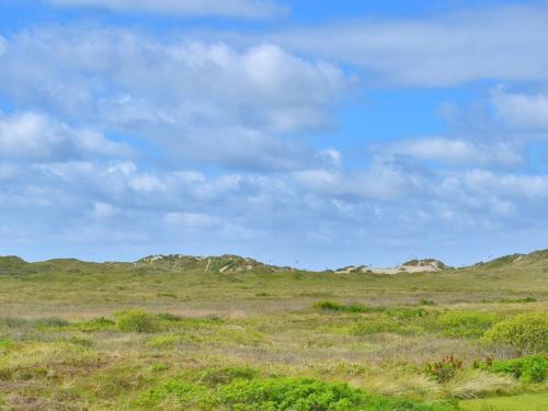a field with rocks in the distance with a cloudy sky at Holiday Home Sohvi - 450m from the sea by Interhome in Lakolk
