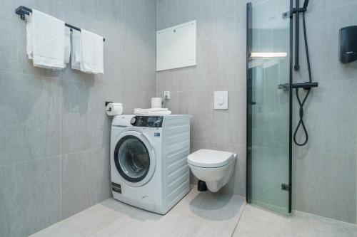 a bathroom with a washing machine and a toilet at MAYA Apartments - Parkveien in Oslo