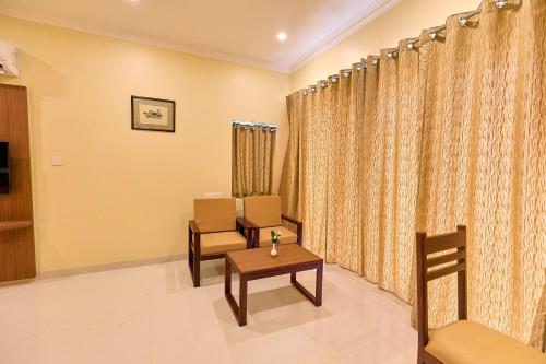 a waiting room with chairs and a table and curtains at ASJ Holiday Villa in Puducherry