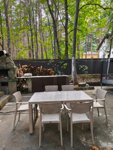 a white table and chairs with trees and a fence at Tskneti in Tsqnetʼi
