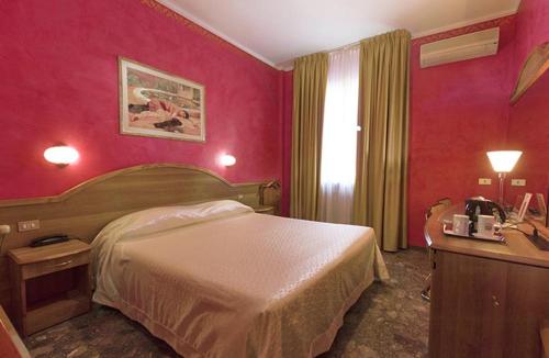 a hotel room with a large bed and red walls at Hotel Europa in Novara