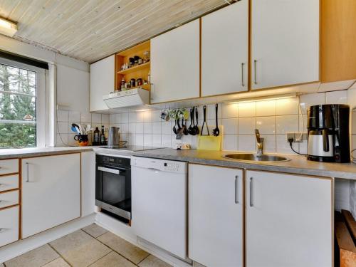 a kitchen with white cabinets and a sink at Holiday Home Annelisa - 200m to the fjord by Interhome in Ulfborg