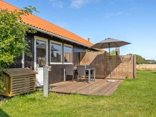 a house with a deck with a table and an umbrella at Holiday Home Arise - 700m from the sea by Interhome in Vejrø