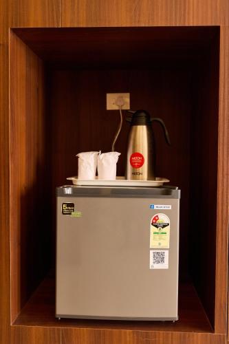 a small refrigerator with a kettle on top of it at ASJ Holiday Villa in Puducherry