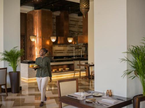 a woman holding a plate of food in a restaurant at Aldhafra Desert Resort, Vignette Collection by IHG in Madīnat Zāyid