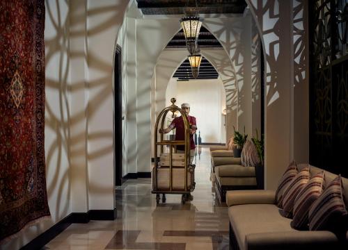 a man standing in a hallway with a grandfather clock at Aldhafra Desert Resort, Vignette Collection by IHG in Madīnat Zāyid