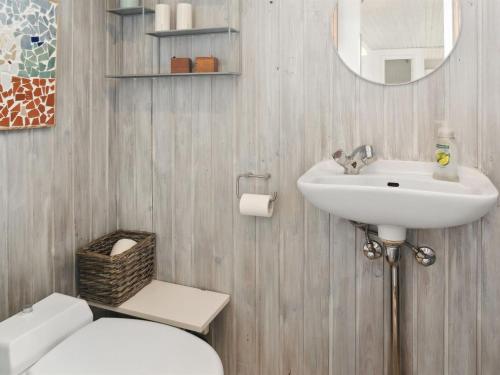 a bathroom with a sink and a toilet and a mirror at Holiday Home Holmwith - 200m from the sea by Interhome in Vesterby