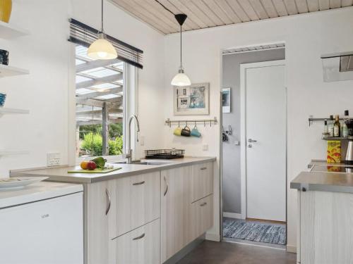a kitchen with white cabinets and a large window at Holiday Home Holmwith - 200m from the sea by Interhome in Vesterby