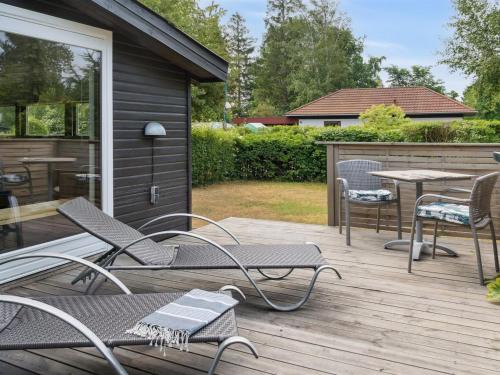 a wooden deck with chairs and a table on it at Holiday Home Holmwith - 200m from the sea by Interhome in Vesterby