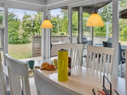 a dining room with a table and chairs and windows at Holiday Home Holmwith - 200m from the sea by Interhome in Vesterby