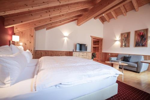a bedroom with a large white bed and a couch at Hotel Sonnenhalde, Arosa in Arosa