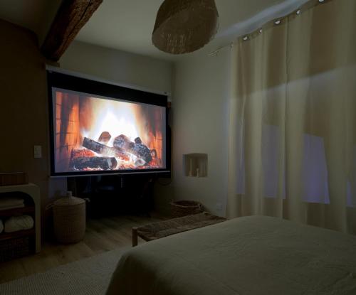 a bedroom with a large screen television with a fireplace at Cocooning and spa in Varages