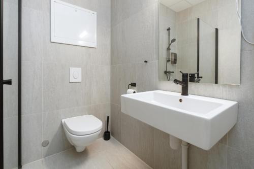 a bathroom with a white sink and a toilet at MAYA Apartments - Parkveien in Oslo