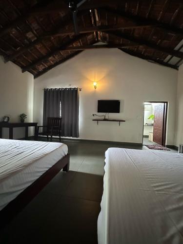 a bedroom with two beds and a flat screen tv at Sky Holiday Homestay Cottages Madikeri Kushalnagar Coorg in Kushālnagar