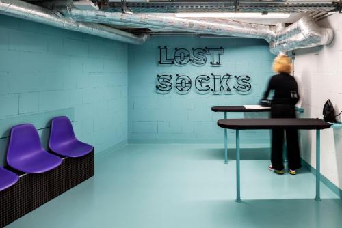 a woman standing in a room with two tables and purple chairs at The Social Hub Berlin Alexanderplatz in Berlin