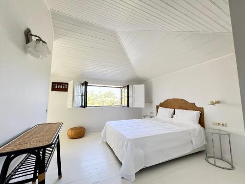a white bedroom with a bed and a table at Quinta de Sá in Vila Nova de Gaia