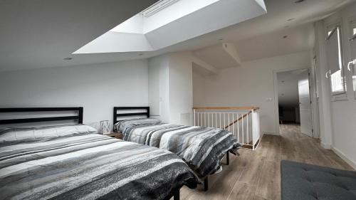 two beds in a white room with a skylight at Casa Florida Hernani in Hernani