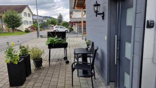 a patio with chairs and potted plants next to a building at Wohnung I im Vierländereck I Auszeit I Rheintal in Rebstein
