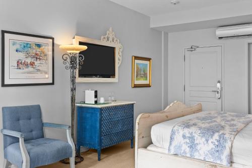 a bedroom with a bed and a chair and a tv at Auberge Place d'Armes in Quebec City