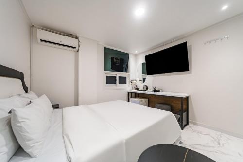 a white bedroom with a bed and a tv at 넘버25호텔 길동점 in Seoul