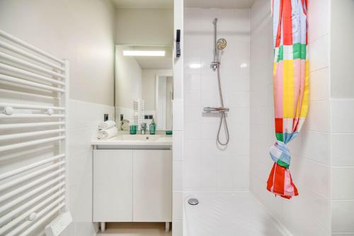 a white bathroom with a shower and a sink at Appart'hôtel Toulouse Zénith in Toulouse