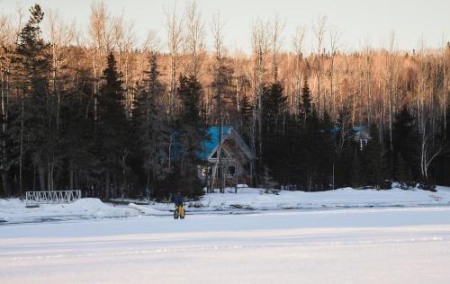 a person standing in the snow in front of a house at Chalets du bout du monde in Gaspé