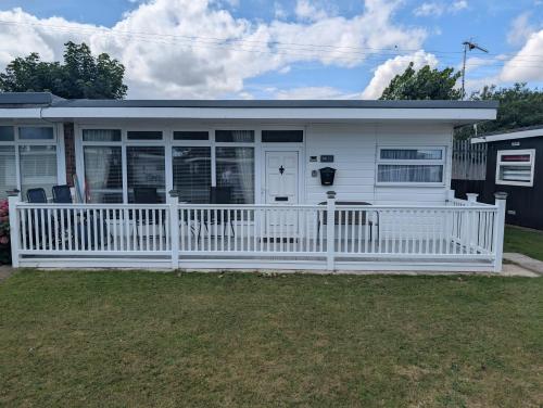 a white mobile home with a white fence at L&L's Lodge, A small but perfectly formed chalet in Chapel Saint Leonards