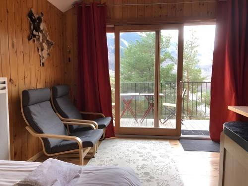 a bedroom with a chair and a balcony at Shangri La in Saint-Jean-Saint-Nicolas