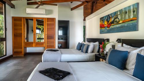 two beds in a hotel room with blue accents at Tulemar in Manuel Antonio