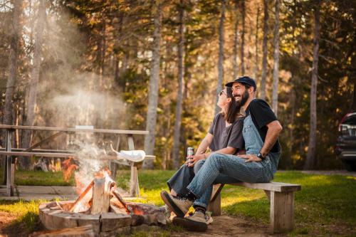 a man and woman sitting on a bench next to a fire at Chalets du bout du monde in Gaspé