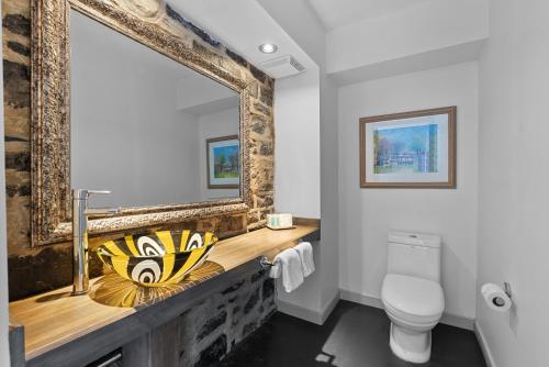a bathroom with a sink and a mirror and a toilet at Auberge Place d'Armes in Quebec City