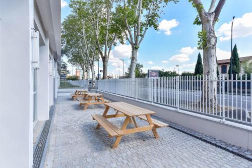 a row of benches on a sidewalk next to a fence at Appart'hôtel Toulouse Zénith in Toulouse