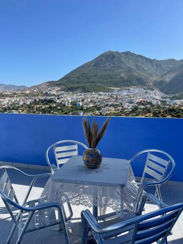 a table with chairs and a vase on a balcony at Dar Chefchauen in Chefchaouene