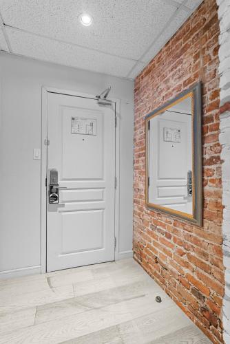 a brick wall with a white door and a mirror at Auberge Place d'Armes in Quebec City