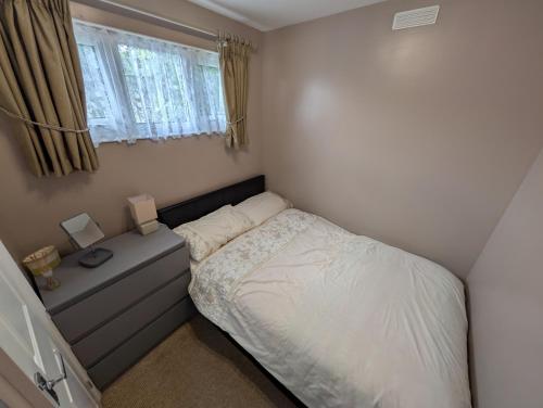 a small bedroom with a bed and a window at L&L's Lodge, A small but perfectly formed chalet in Chapel Saint Leonards