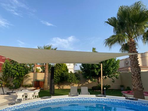 a white umbrella over a pool in a yard at Laguna del Flamenco in Torrevieja