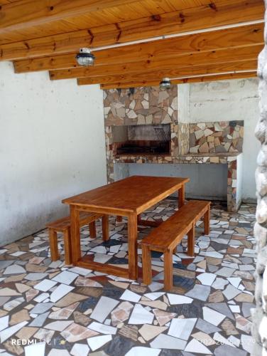 a wooden table and benches in front of a fireplace at Cabañas KAIZEN in Santa María