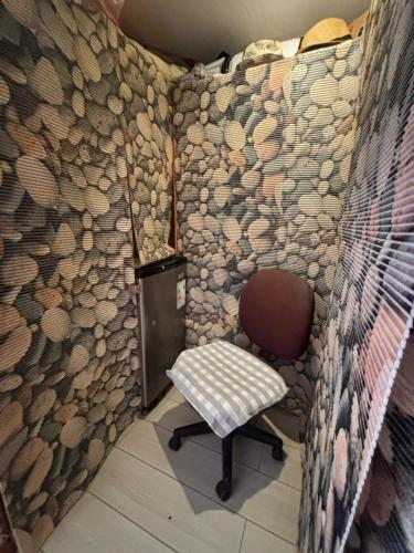 a small room with a chair and a wall with logs at Hostal California in El Cerrillo