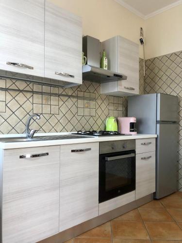 a kitchen with white cabinets and a stainless steel refrigerator at BeB Lucky House Francesca in Scafati