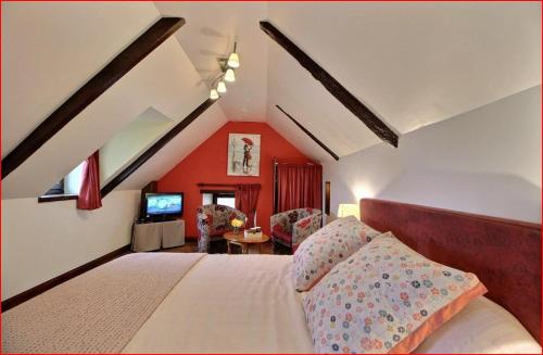 a bedroom with red walls and a bed and a tv at Gîte De Kerberso in Pléhédel