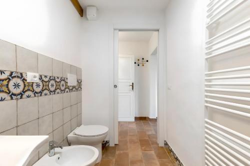 a white bathroom with a toilet and a sink at Fattoria le Caprine in Querce