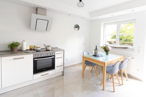 a white kitchen with a wooden table and a dining room at Ferienwohnung Steuerwald in Bobenheim am Berg