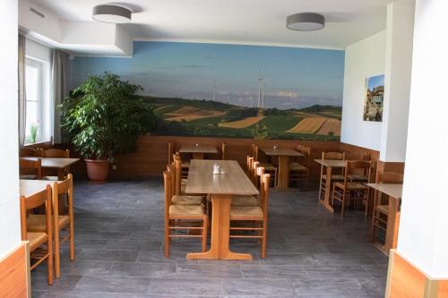 a restaurant with tables and chairs and a painting on the wall at OEKOTEL Traiskirchen in Traiskirchen