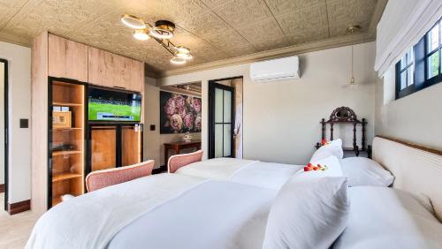 a bedroom with two beds and a tv at Batavia Boutique Hotel in Stellenbosch