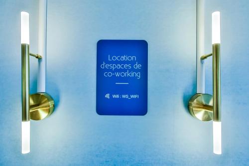 un panneau bleu sur le mur d'une salle de bain avec deux lumières dans l'établissement WS Opéra - Duphot, à Paris