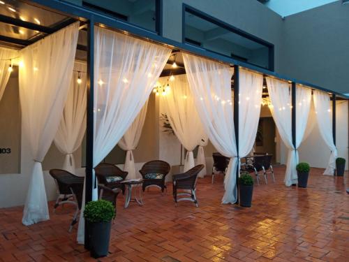 a room with white curtains and chairs and tables at Pousada São Gerônimo in Matinhos