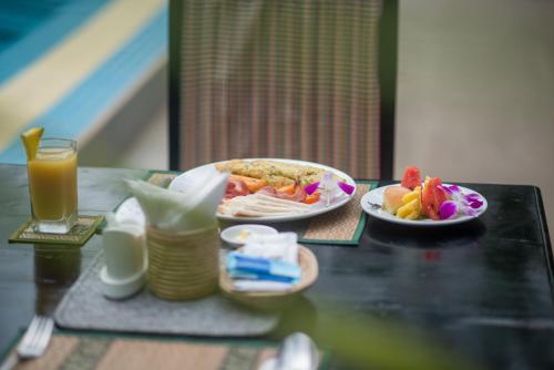 a table with two plates of food and a glass of orange juice at Reasey Boutique Villa in Siem Reap