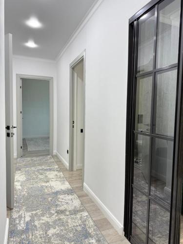 an empty hallway with white walls and glass doors at Asel Residential Complex, stylish 3-room apartment in Atyraū