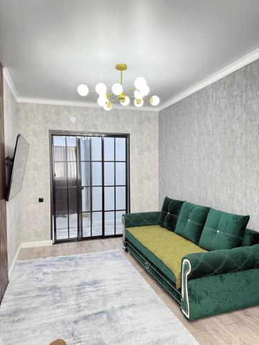 a living room with a green couch and a window at Asel Residential Complex, stylish 3-room apartment in Atyraū