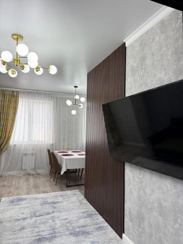 a living room with a dining table and a flat screen tv at Asel Residential Complex, stylish 3-room apartment in Atyraū